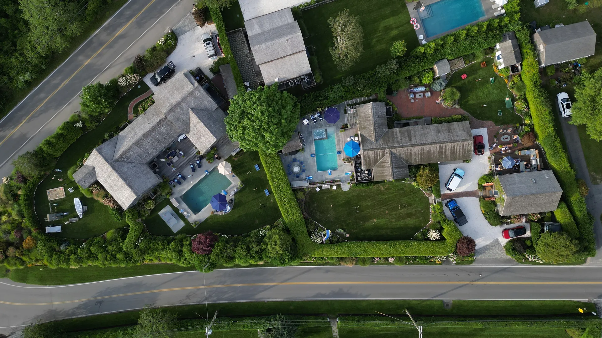 A straight-down aerial of the compound: the houses, gravel drives and hedged lawns laid out together, with the pools and bluestone terraces tucked between them.