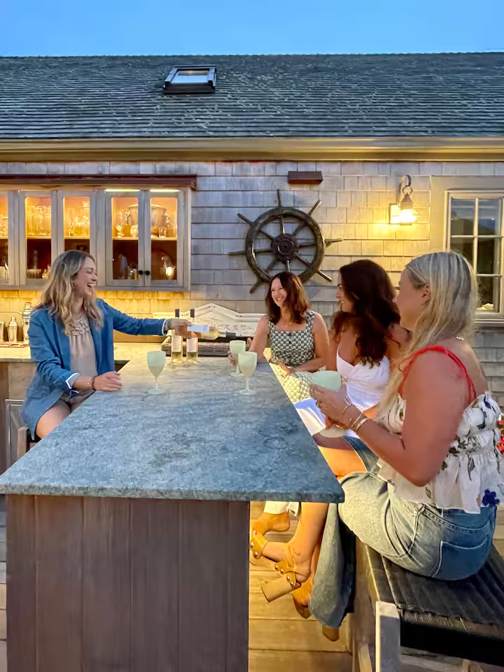 The same outdoor bar counter at dusk, the post lanterns lit and drinks set along the counter.
