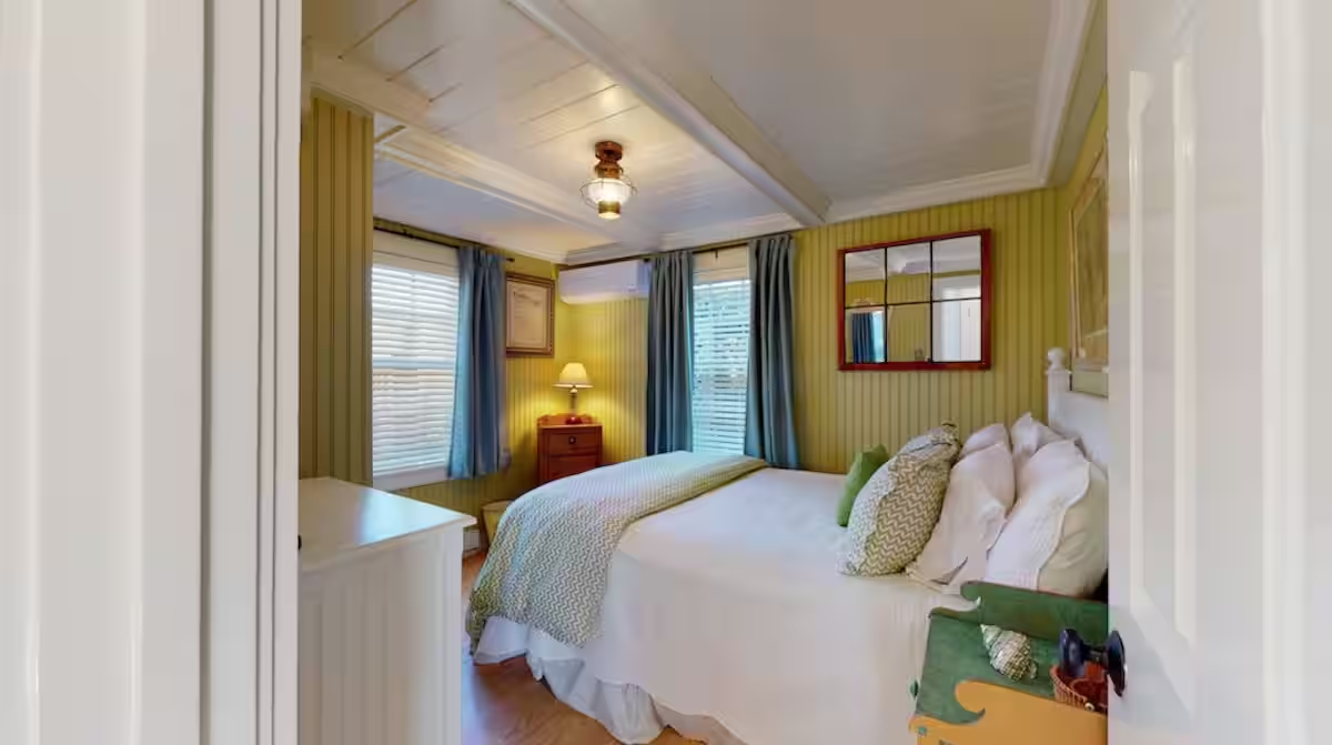 A bedroom in Crew with green walls and a made bed.