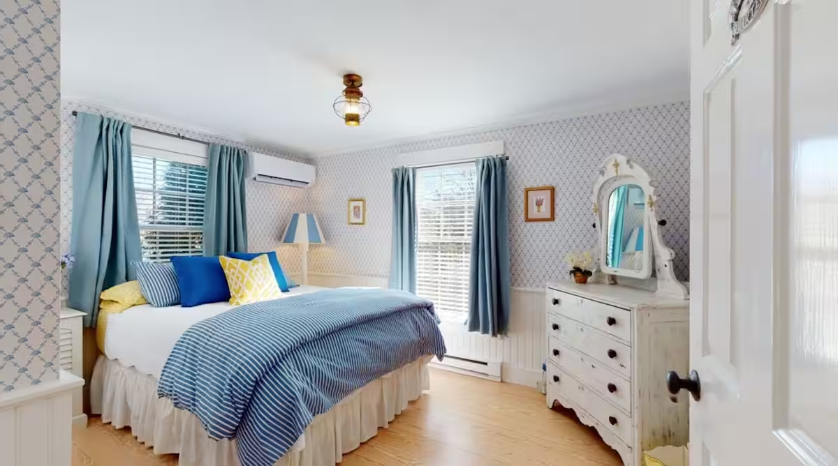 A bedroom in Crew with a made bed and striped textiles.