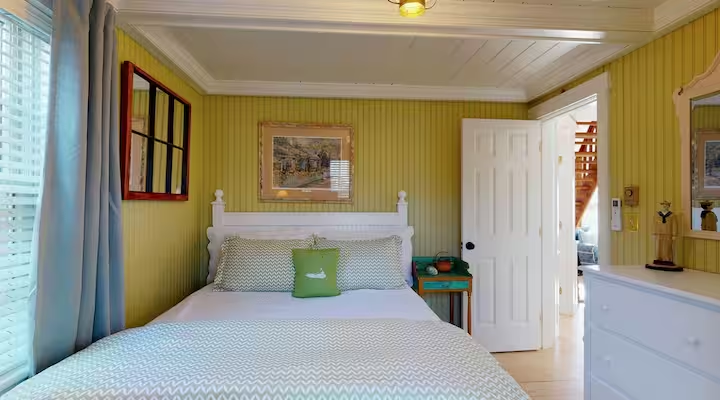 A bedroom in Crew with warm yellow walls and a made bed.