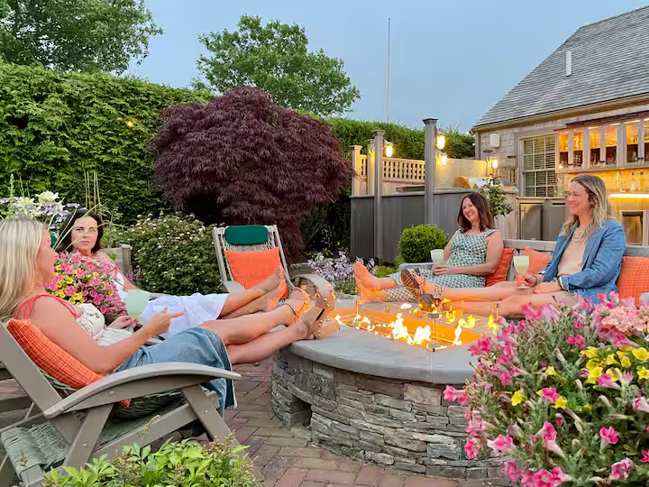 The fire table lit at dusk with guests gathered in the sling chairs around it.