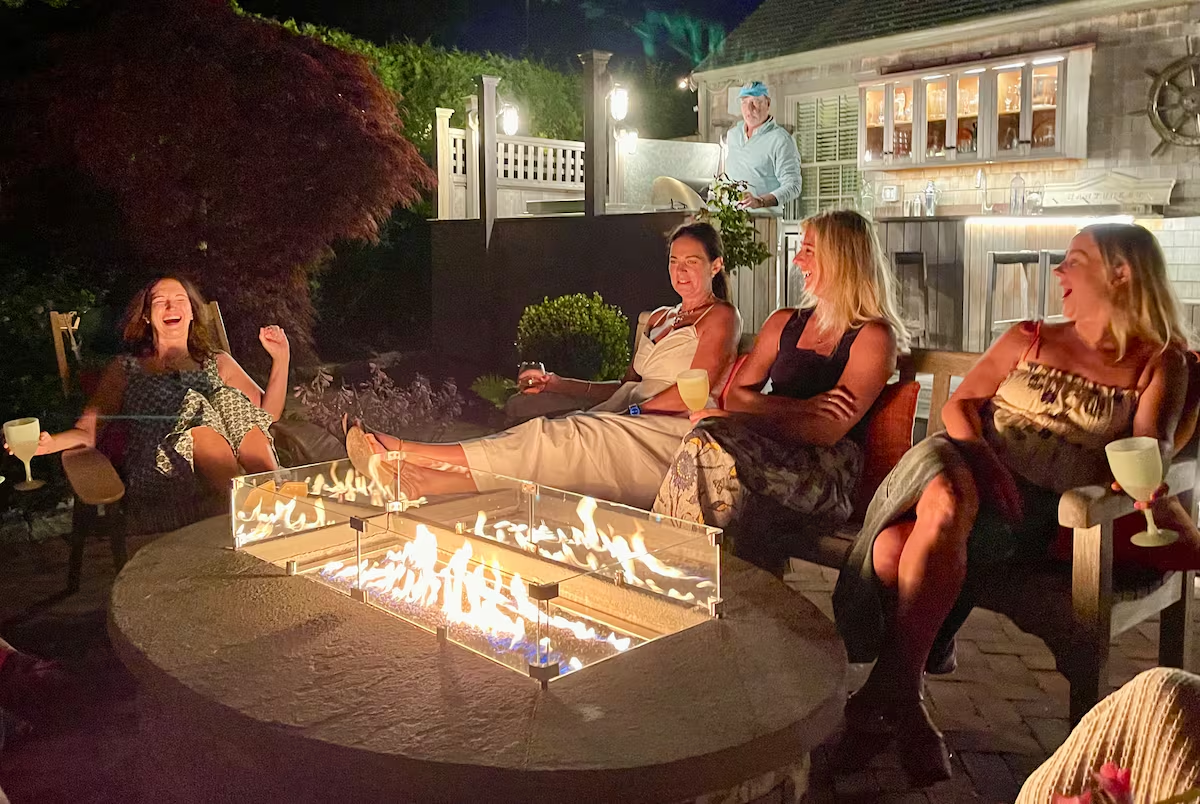 The same terrace after dark, the flame bar throwing light across the brick.