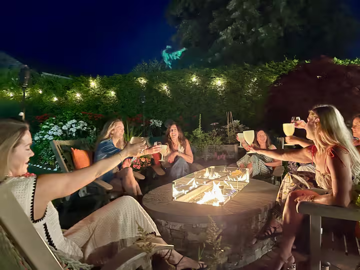 A toast around the fire table late in the evening, faces lit by the flame.