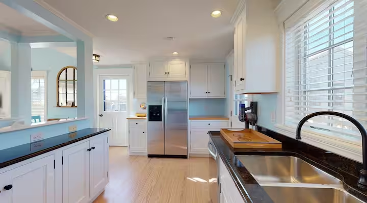 Crew's indoor kitchen with painted cabinetry, open shelving and counters running either side of the range.